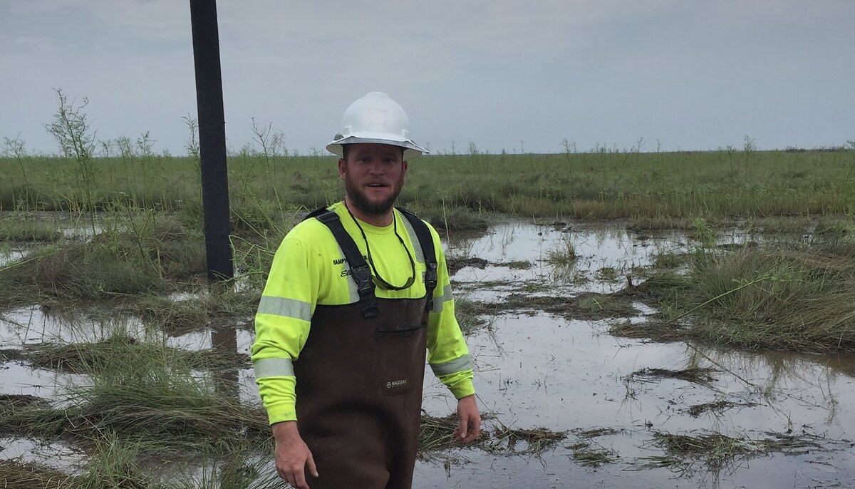 Lineman in waders working a flooded utility right-of-way